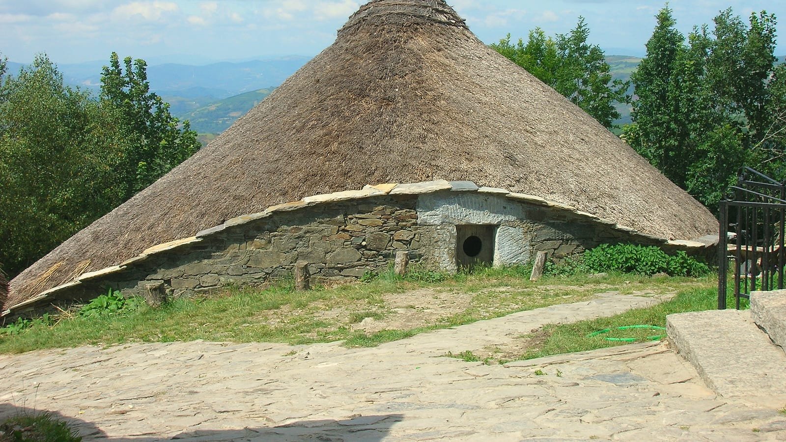 Palloza com telhado de colmo em O Cebreiro com montanhas ao fundo, etapa Villafranca del Bierzo – O Cebreiro