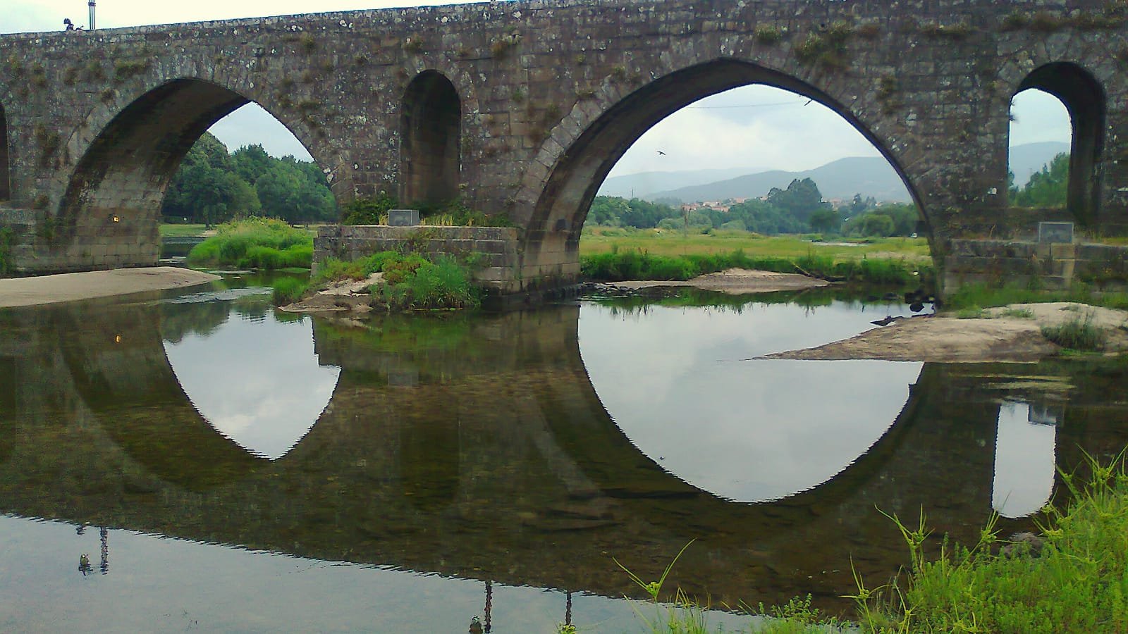 Arcos da ponte medieval de Ponte de Lima refletidos no rio Lima, etapa Barcelos – Ponte de Lima